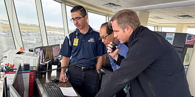 Embry‑Riddle researchers Dr. Jianhua Liu and Andrew Schneider are collaborating on a project that uses artificial intelligence to improve the clarity and safety of radio communications between pilots and air traffic controllers. Here, they are pictured with lead flight supervisor Chris Deputy (left) in the Flight Supervisor Tower.