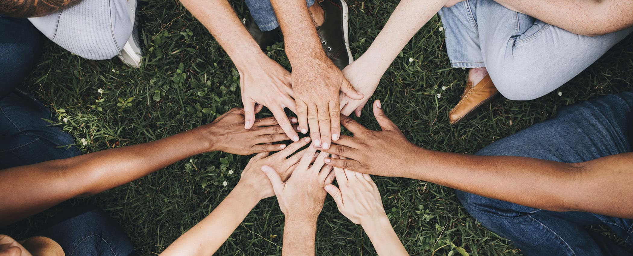 People stacking hands together in the park