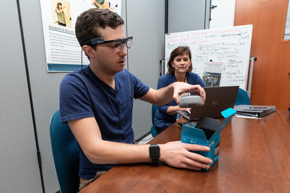 Graduate student Jacob Benedict works with Dr. Barbara Chaparro to demonstrate how they can use the TobiiPro augmented reality glasses to observe someone doing a product unboxing in the Human Factors User Experience Lab.