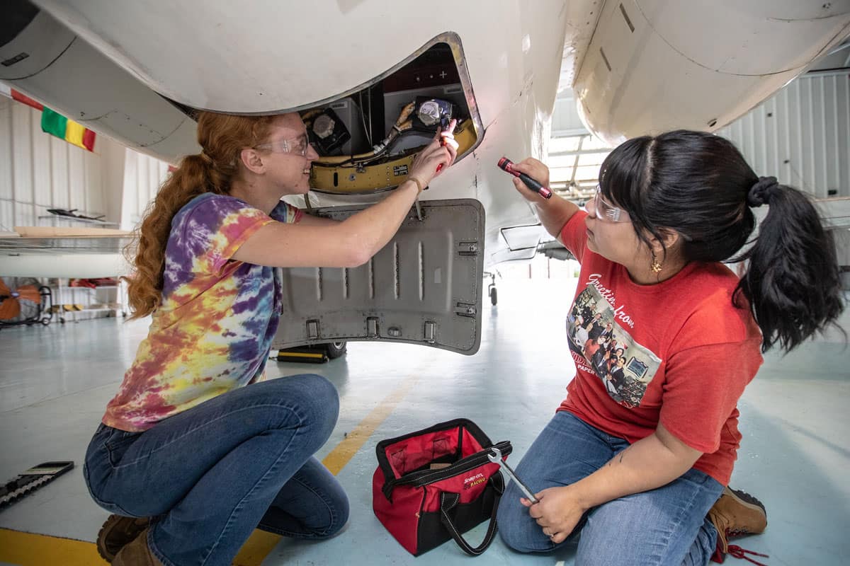 Two women work on a plane.