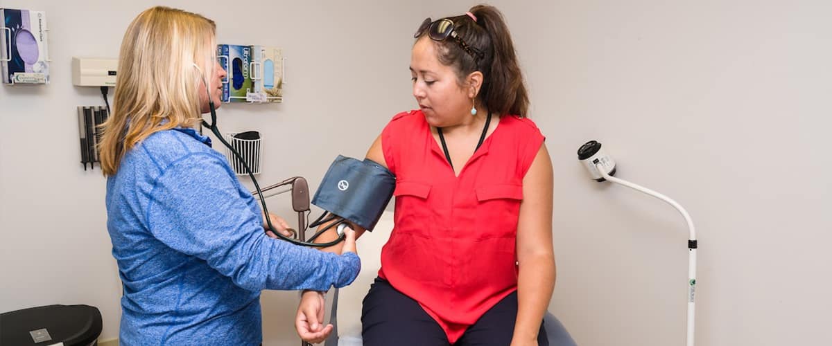 Woman takes blood pressure from patient.