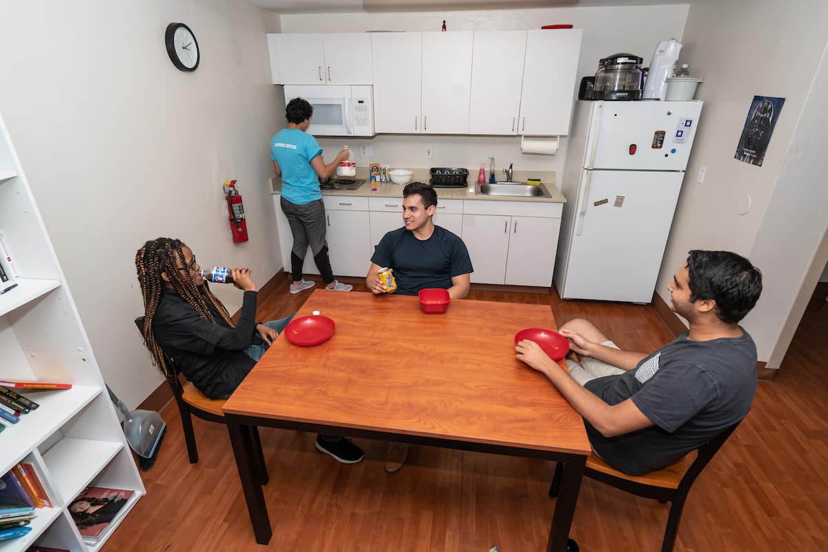 Students sit in an O'connor Hall kitchen at the table.