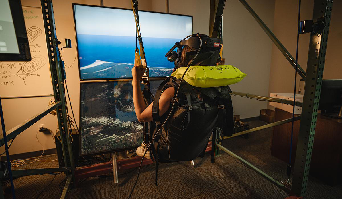 Student sits in a swing for virtual reality.
