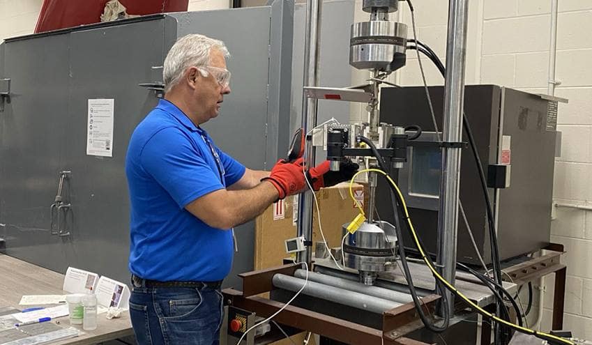 Dr. Mello with an MTS frame and furnace for high-temperature mechanical experiments at the Lehman Building.