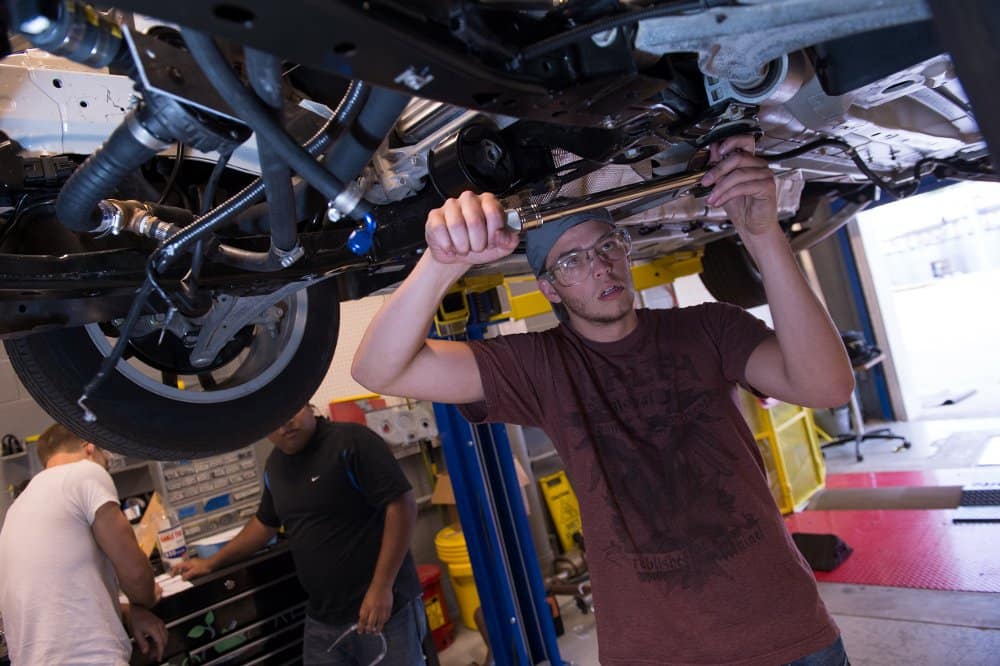 A student works on the underside of the EcoCar