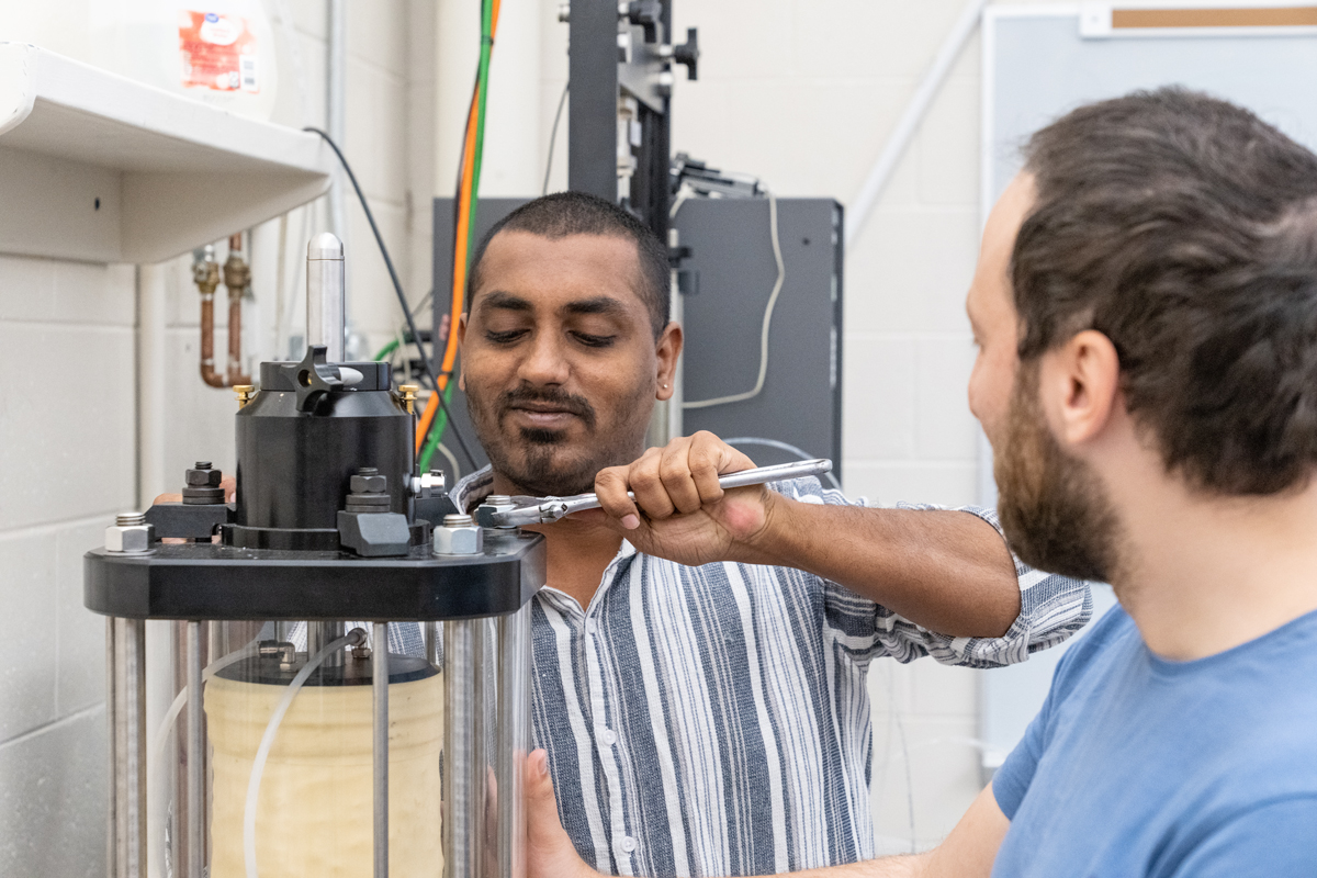 Two students work on a machine in the Advanced Geotechnical Laboratory