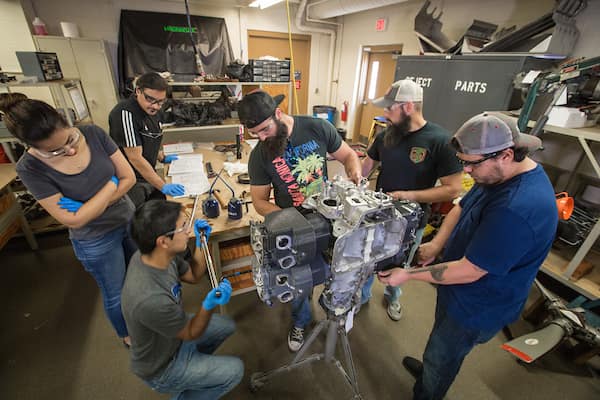 Professor and students work around an engine