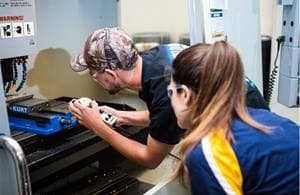 Students work on a drill press in the CNC and Welding Laboratory