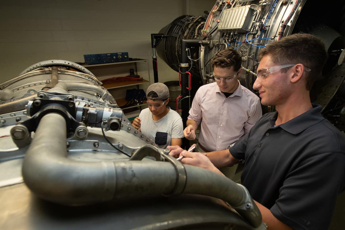 From Left: Tea Galon-Walraven, Andrew Guggenheim, and Andrew Masterson work on a turbine engine in the Emil Buehler Aviation Maintenance Science Building. They are part of a cohort of AMS students who were awarded the "Purple Runway Scholarship" from FedEx, for $5,000, at Embry-Riddle Aeronautical University's Daytona Beach Campus. Photo taken prior to pandemic and social distancing/masking requirements. (Embry-Riddle/David Massey)