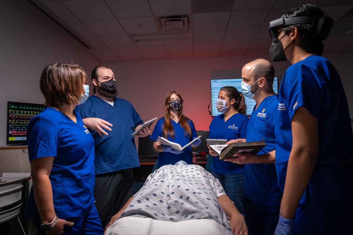 Students surround a patient during lab research.
