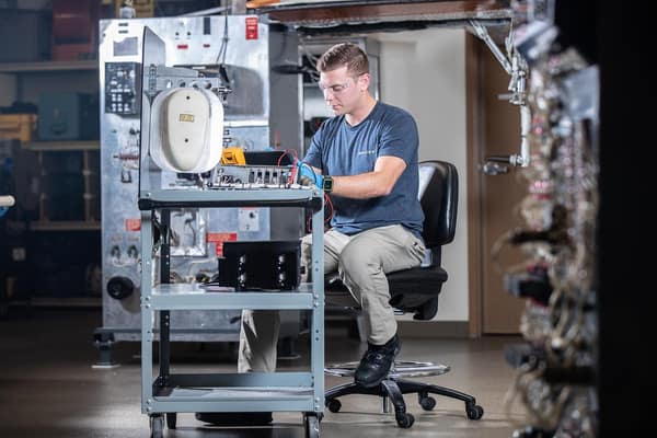 A person sitting at a desk working in the Payload Applied Technology and Operations lab.