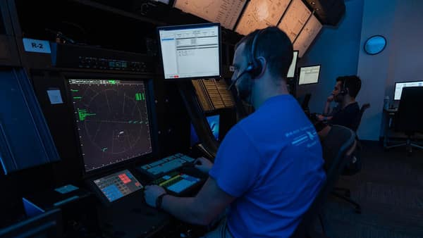 A student wearing headphones, working at a radar station.