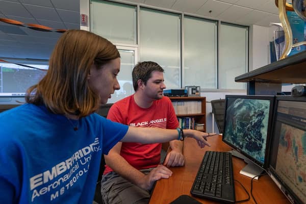 Two students sitting at a desk studying the weather on a computer. 