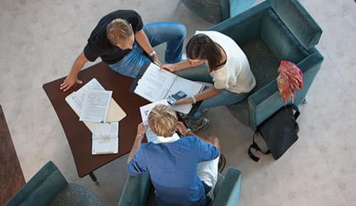 three students work at a desk