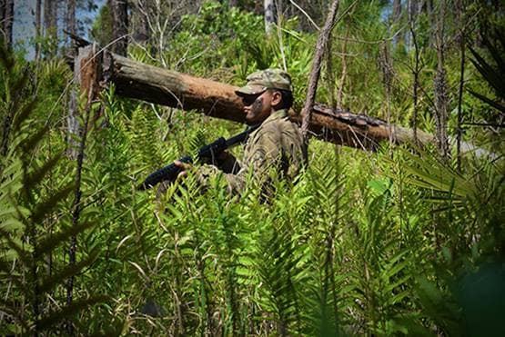 Soldier carrying gun in the woods