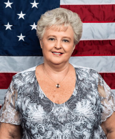 Kaye Decker standing in front of an American flag.