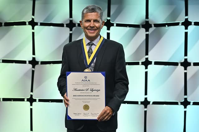 Tasos Lyrintzis holds an award.