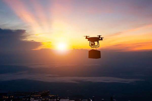 A drone delivers a package during a sunset