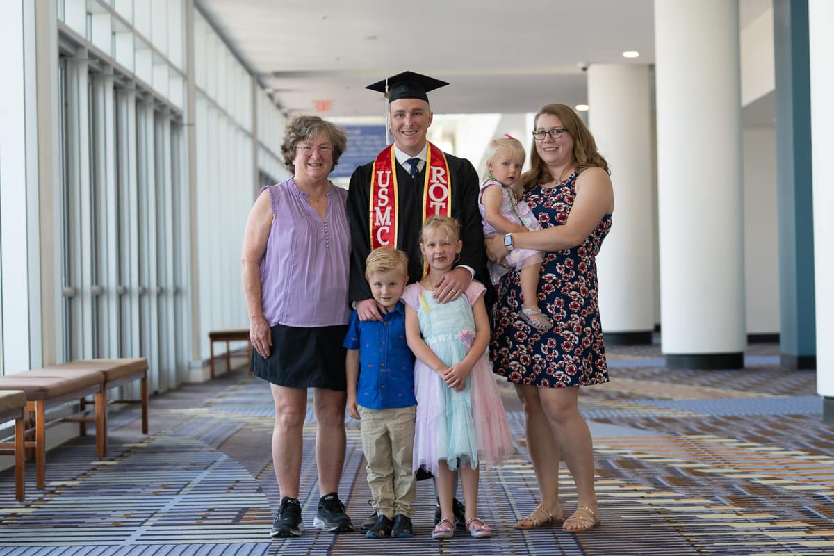 Family of five in hallway, with male graduate in the center